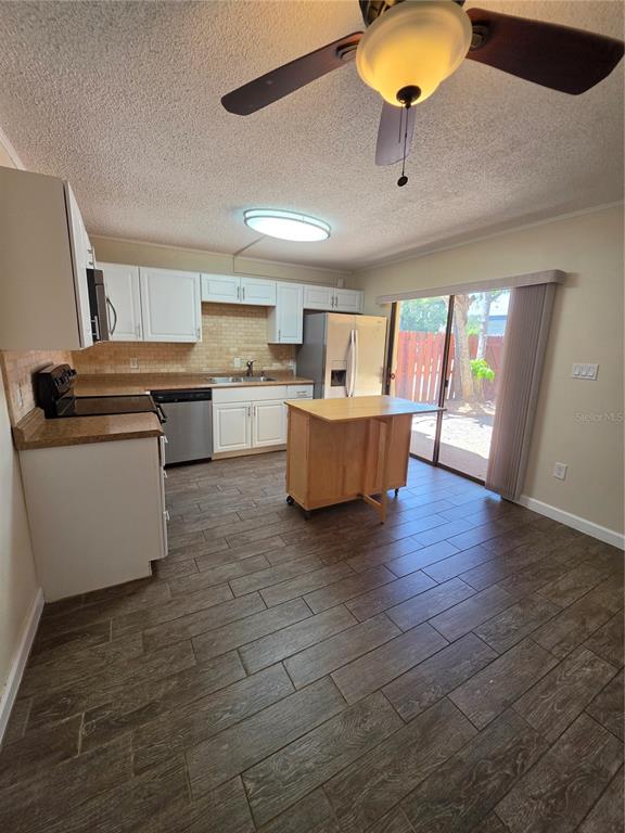 A kitchen with white cabinets, a portable island, and wood-look tile flooring — 3824 SAXON DRIVE, NEW SMYRNA BEACH, FL