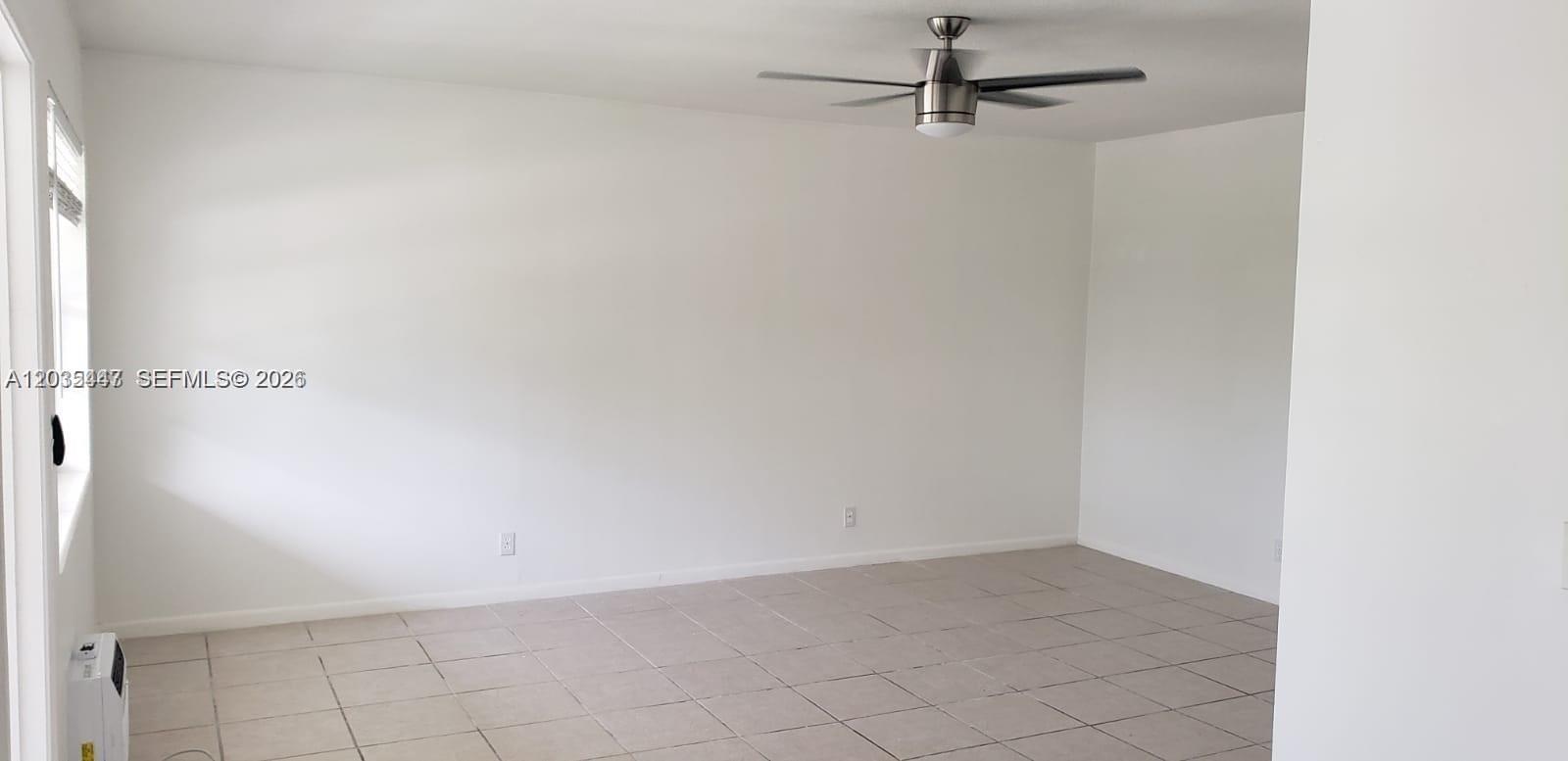 An empty room features white walls, light-colored tile flooring, and a ceiling fan — 320 Fanshaw H # 320, Boca Raton FL 33434, BOCA RATON, FL