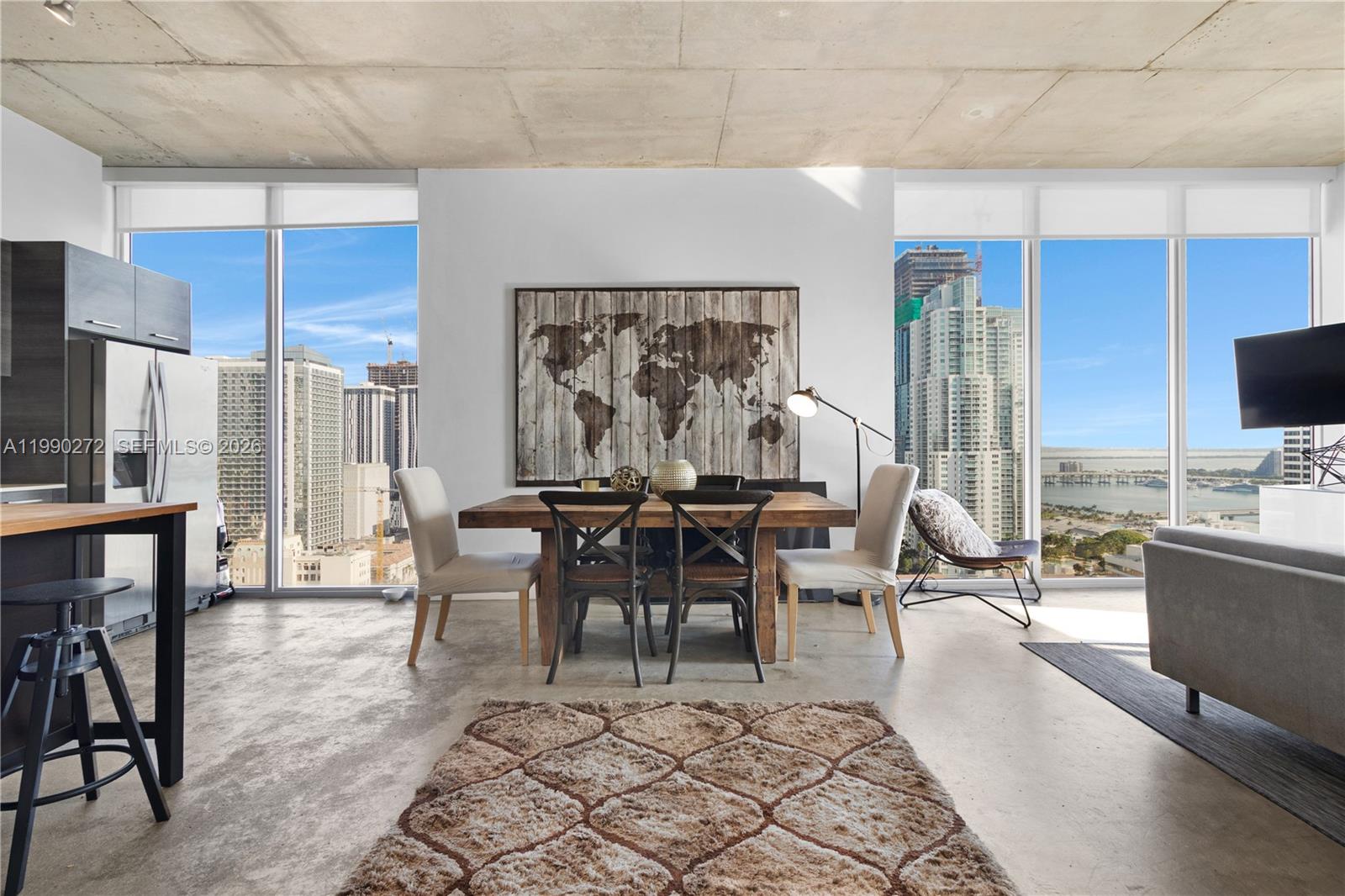 A dining area with a wooden table and world map art features concrete ceilings and floors — 151 SE 1st St # 2802, Miami FL 33131, MIAMI, FL