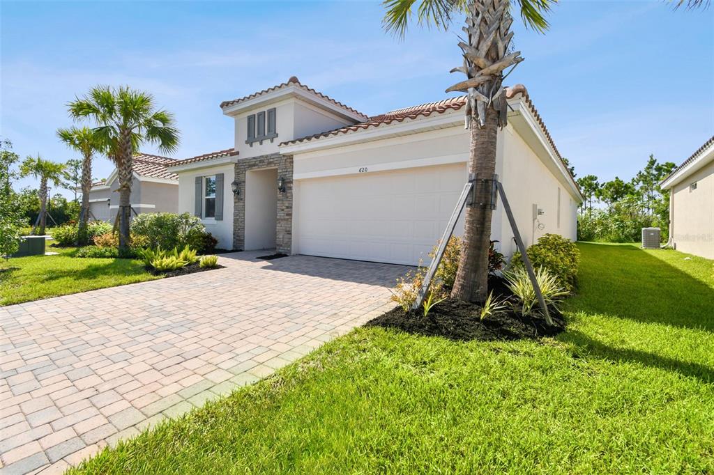 A single-story house with a beige stucco exterior, stone accents, and a paved driveway — 620 NASTURTIUM COURT, NOKOMIS, FL
