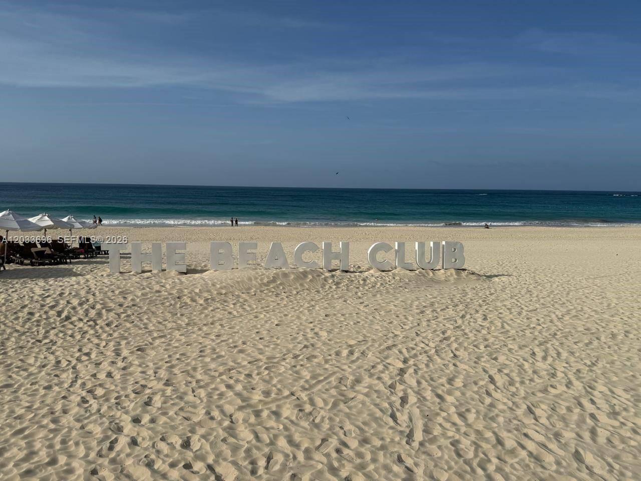 A sandy beach features large, freestanding letters spelling THE BEACH CLUB near the shoreline — 1 Cana Rock # 215, FL