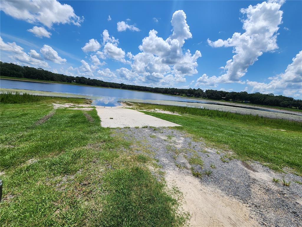 A concrete boat ramp leads into a lake surrounded by grassy fields and trees — LOT 21 SW RAINBOW LAKES BOULEVARD, DUNNELLON, FL