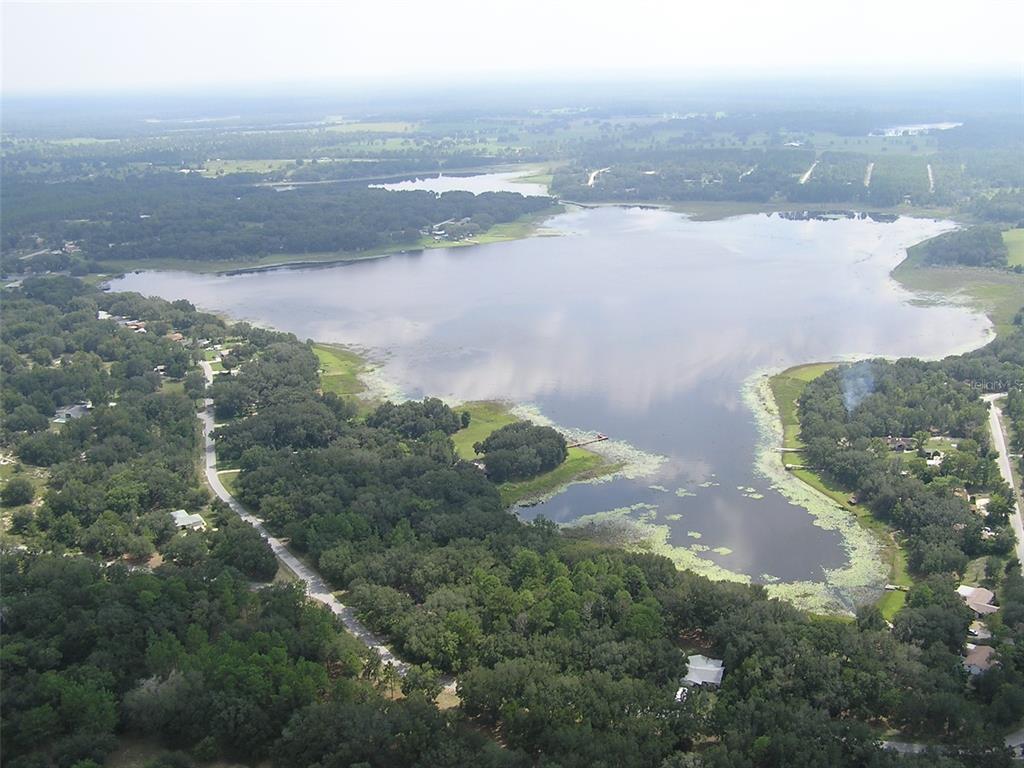 An aerial view shows a large lake surrounded by dense trees and residential properties — LOT 21 SW RAINBOW LAKES BOULEVARD, DUNNELLON, FL