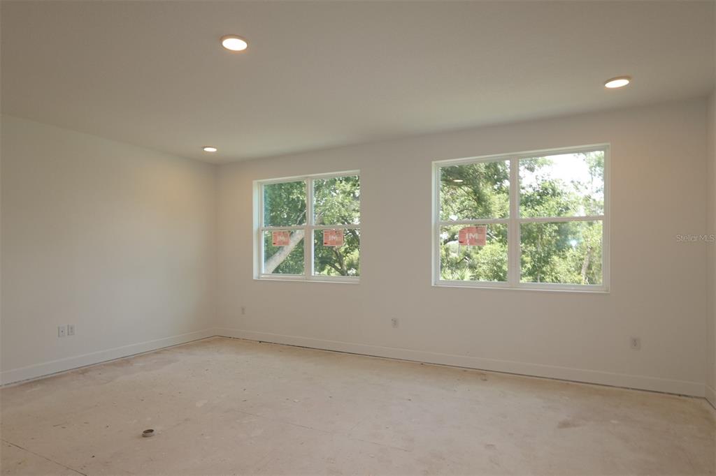 An open-concept kitchen and living area features white cabinetry, light wood-look flooring, and recessed lighting — 3850 WOLVES CREEK PLACE, APOPKA, FL