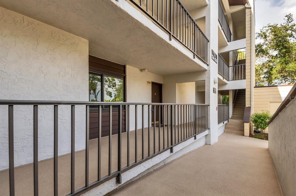 An exterior view of an apartment building walkway with metal railings and a staircase — 2753 ORCHID OAKS DRIVE UNIT 104, SARASOTA, FL