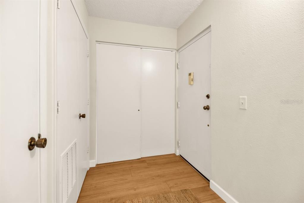 An entryway features wood-look flooring, a white front door, and two sets of white closet doors — 2753 ORCHID OAKS DRIVE UNIT 104, SARASOTA, FL