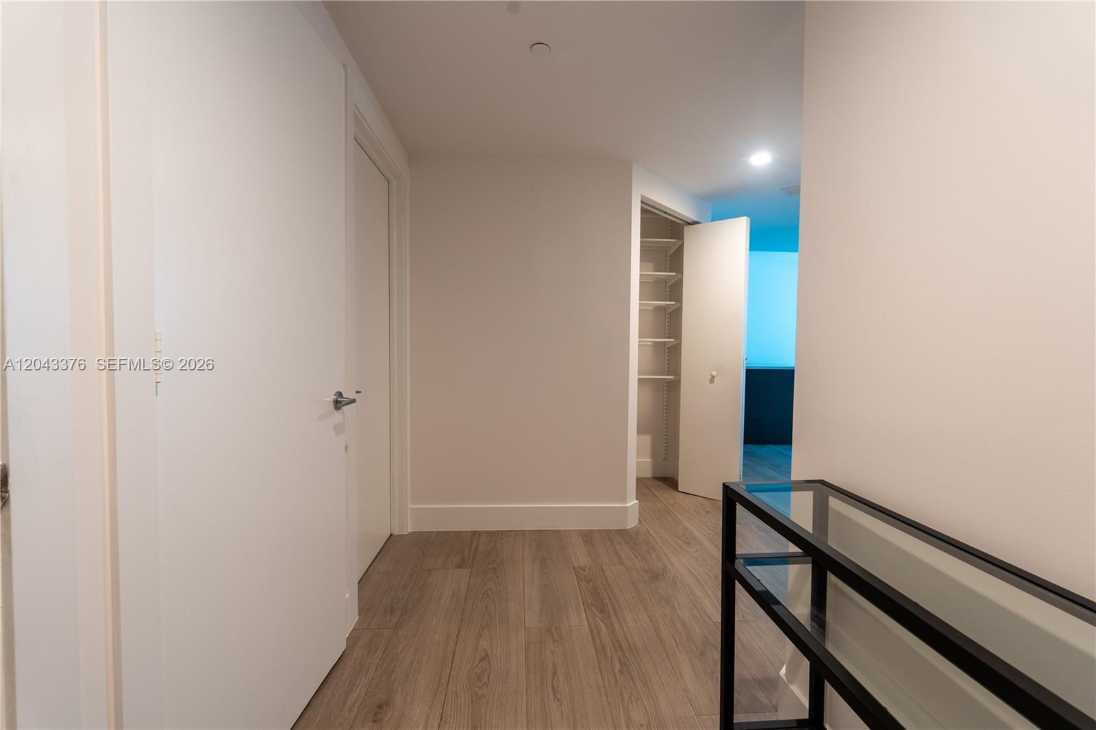 A hallway features light wood-look flooring, white walls, a closed door, and an open closet — 500 Brickell Ave # 1407, Miami FL 33131, MIAMI, FL