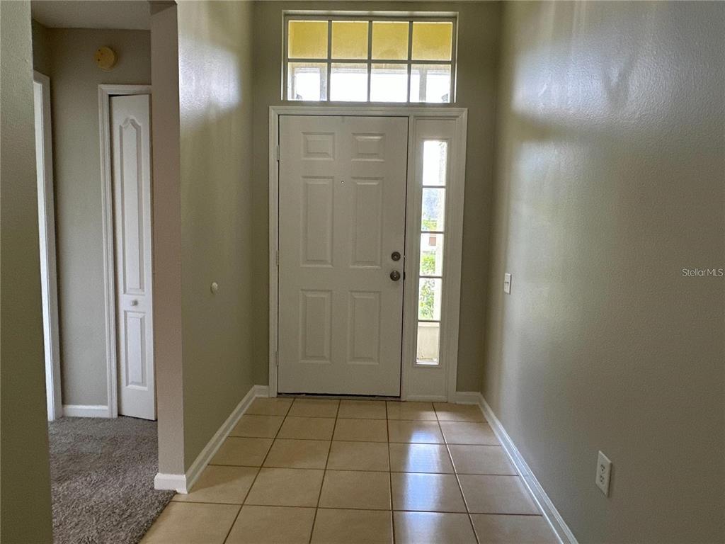An entryway with tiled flooring, a white front door with a sidelight, and a transom window — 30747 BURLEIGH DRIVE, WESLEY CHAPEL, FL