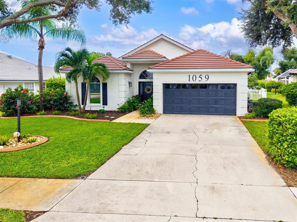A single-story house with a tiled roof, a dark garage door, and a concrete driveway — 1059 TRUMAN STREET, NOKOMIS, FL