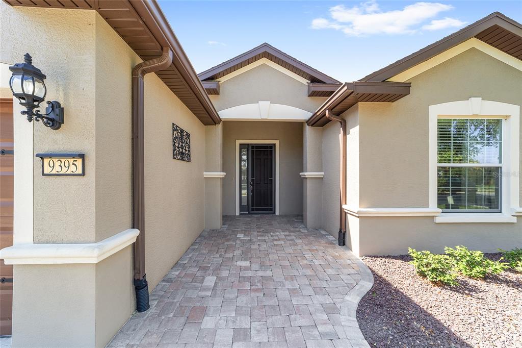 The exterior of a house features a paved walkway leading to a recessed front entrance — 9395 SW 66TH LOOP, OCALA, FL
