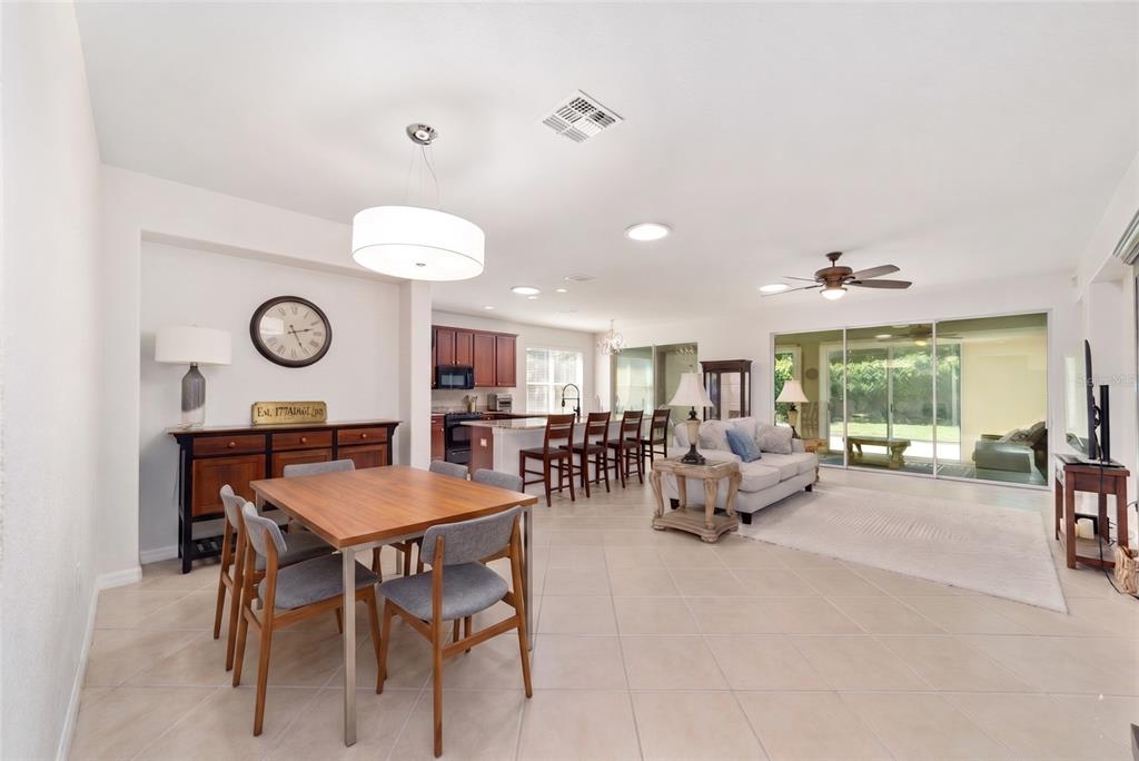 An open-concept living and dining area features tile flooring, a kitchen island, and sliding doors — 9395 SW 66TH LOOP, OCALA, FL