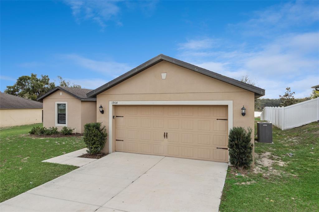 A tan, single-story house with a two-car garage and a concrete driveway — 1904 PIEDMONT COURT, MASCOTTE, FL