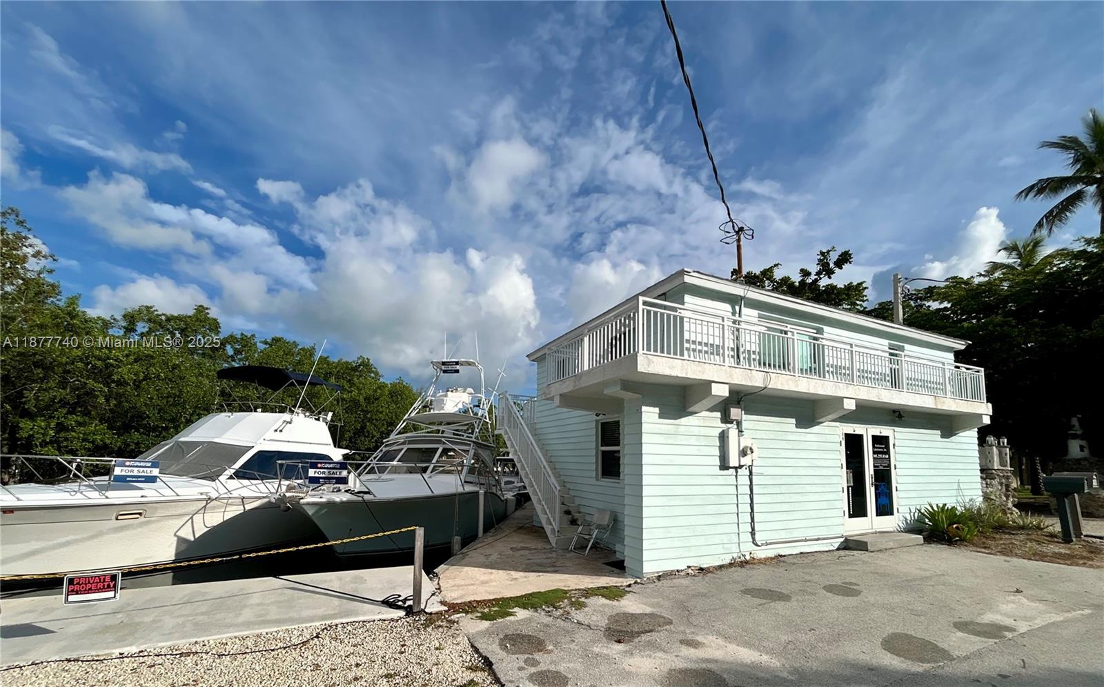 A light blue two-story building sits next to two boats docked in a canal — 108 Madeira Rd, Islamorada FL 33036, ISLAMORADA, FL