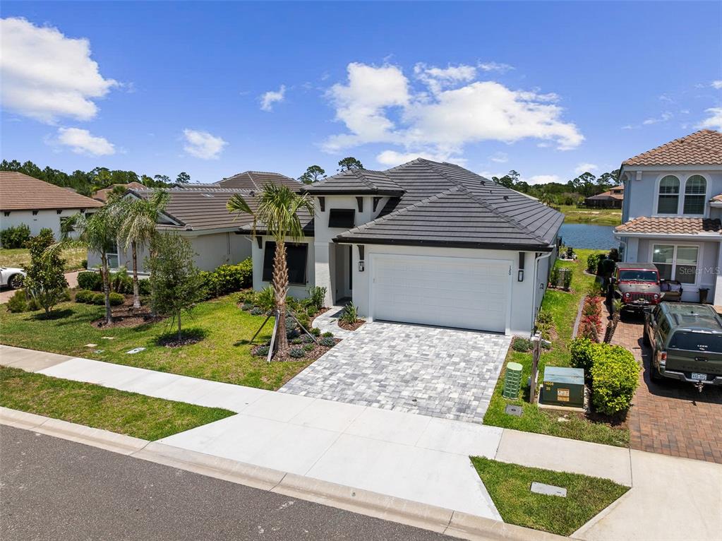 A single-story house with a gray tile roof, white garage door, and paver driveway — 120 DEL PALMA DRIVE, PALM COAST, FL