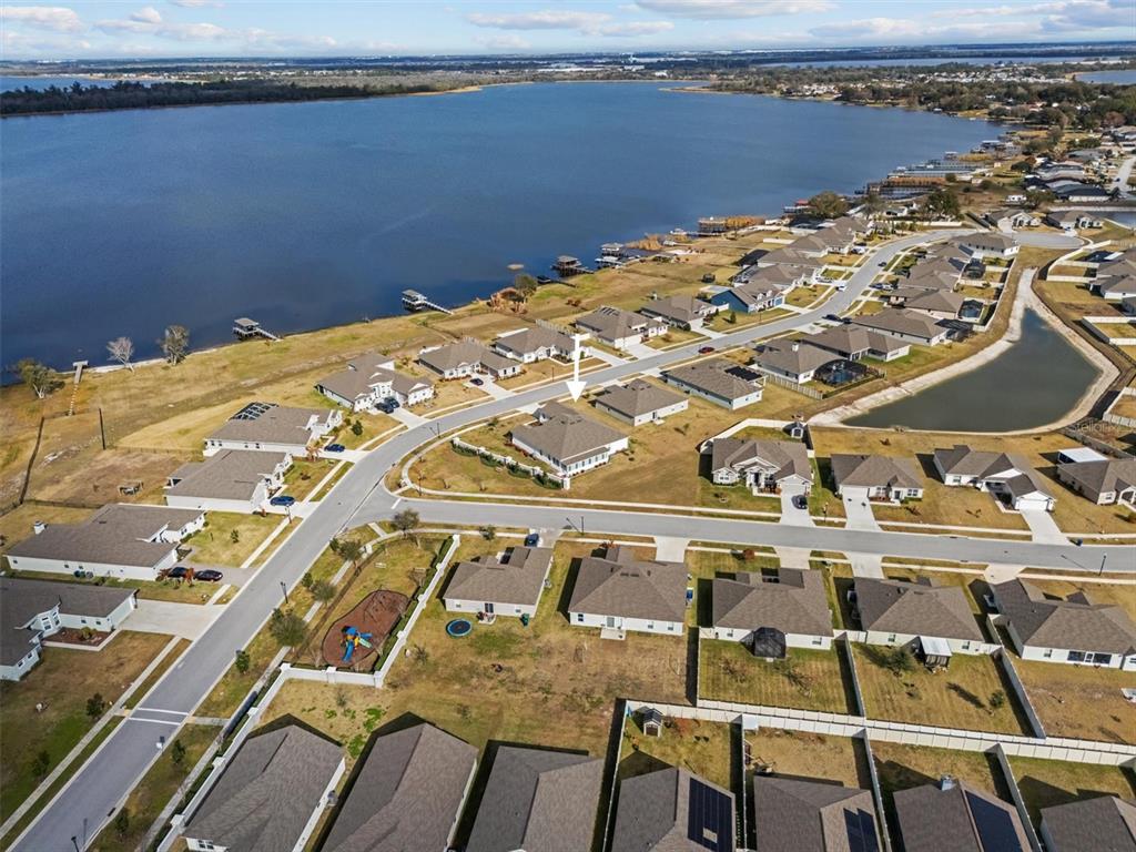 An aerial view shows a suburban neighborhood with houses near a large lake — 530 SANCTUARY BOULEVARD, WINTER HAVEN, FL