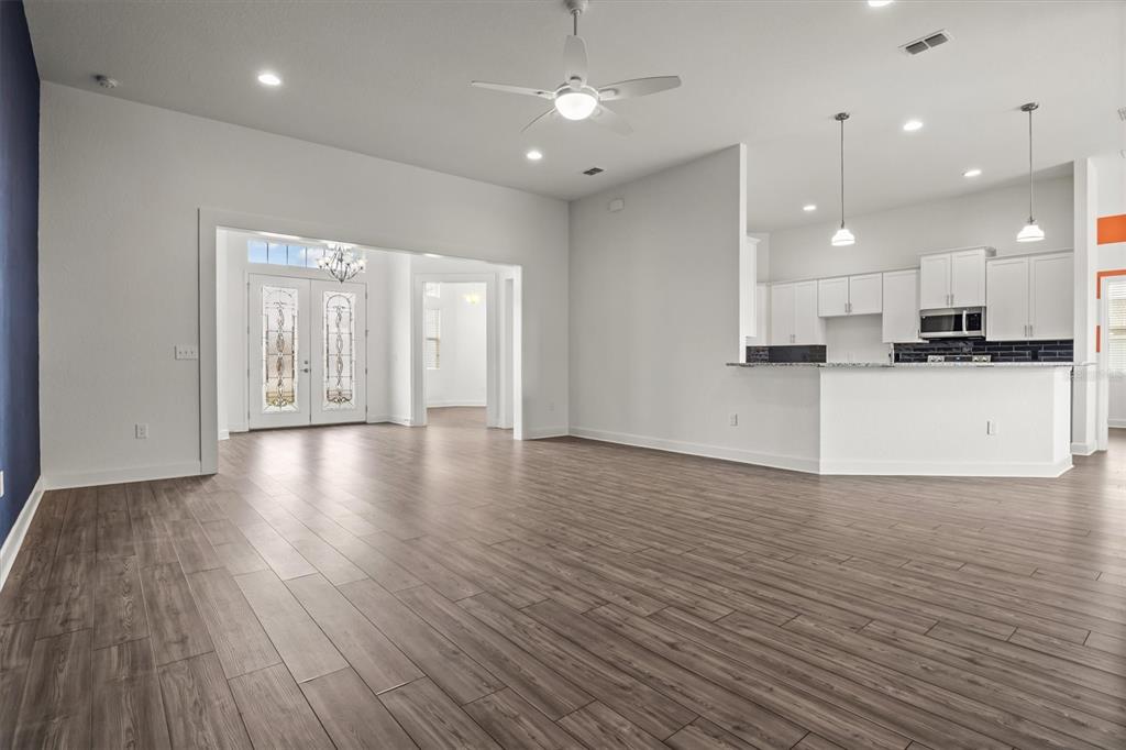 An open-concept living area features wood-look flooring, a ceiling fan, and an adjacent kitchen — 530 SANCTUARY BOULEVARD, WINTER HAVEN, FL