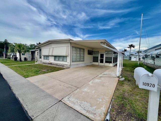 A single-story mobile home with a carport and a mailbox in the foreground — 10920 INDEPENDENCE DRIVE, PORT RICHEY, FL