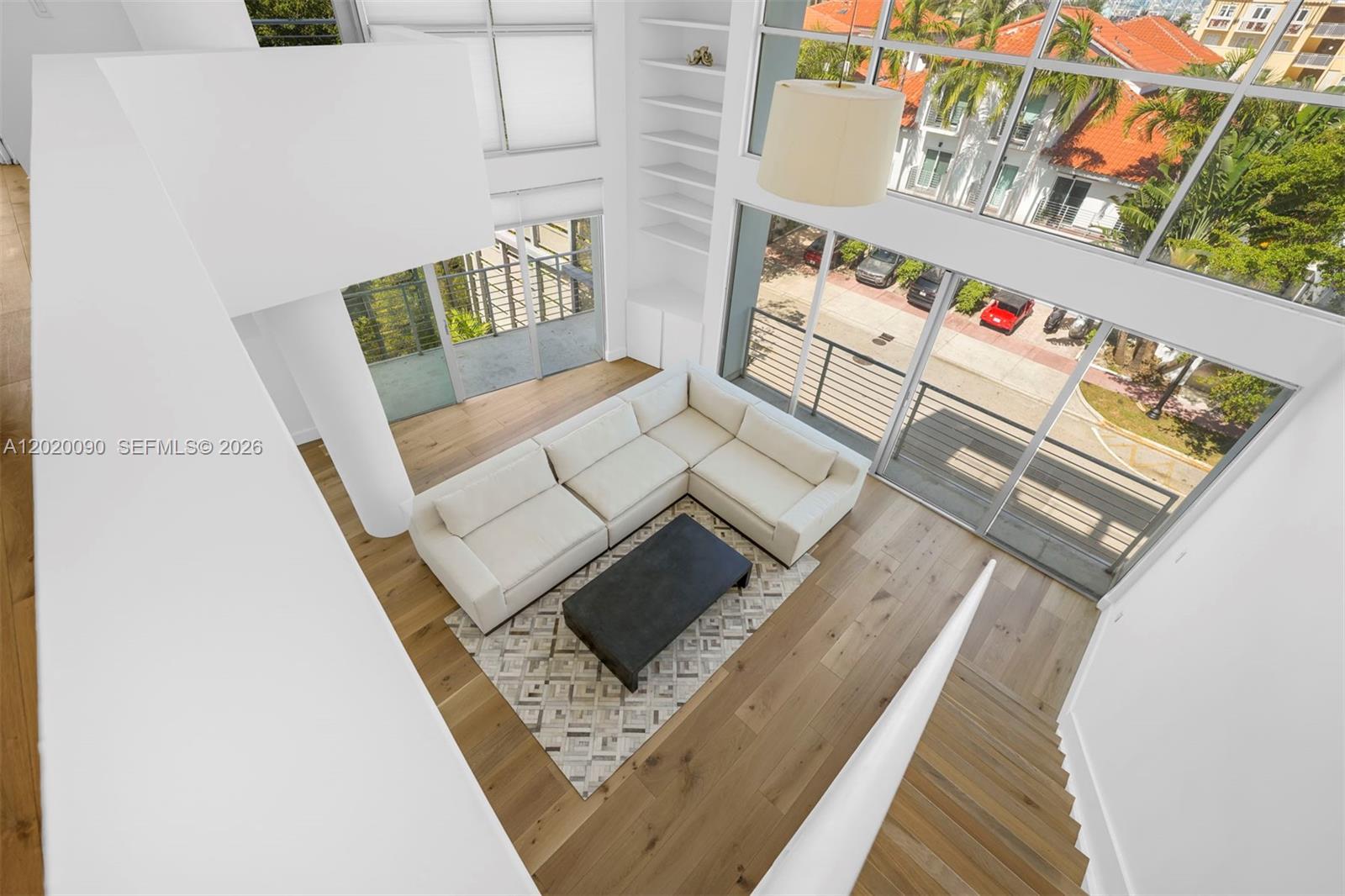 A high-angle view of a modern living room with a sectional sofa and floor-to-ceiling windows — 221 Jefferson Ave # 10, Miami Beach FL 33139, MIAMI BEACH, FL