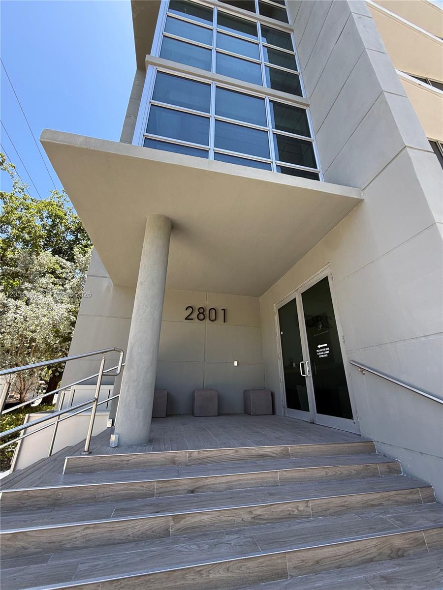 A modern building entrance features concrete stairs, a large support pillar, and glass doors — 2801 SW 3rd Ave, Miami FL 33129, MIAMI, FL