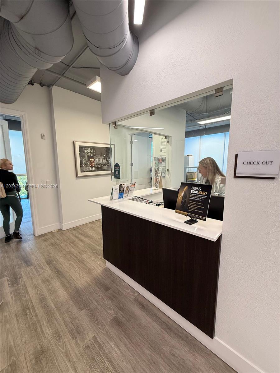 A reception desk with a glass partition sits in a room with wood-look flooring — 2801 SW 3rd Ave, Miami FL 33129, MIAMI, FL