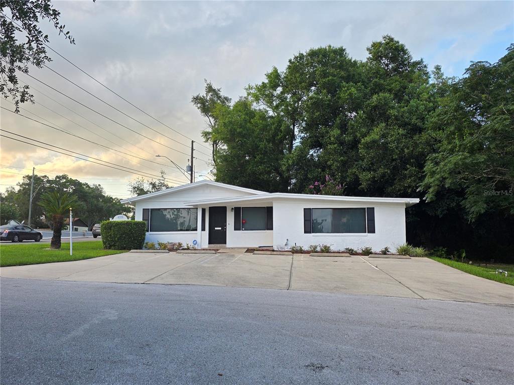 A white single-story house with a flat roof and a large concrete parking area — 498 ESTHER LANE, ALTAMONTE SPRINGS, FL
