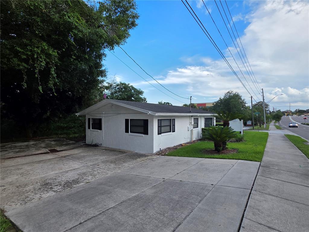 A white, single-story building with a concrete driveway sits next to a sidewalk and road — 498 ESTHER LANE, ALTAMONTE SPRINGS, FL