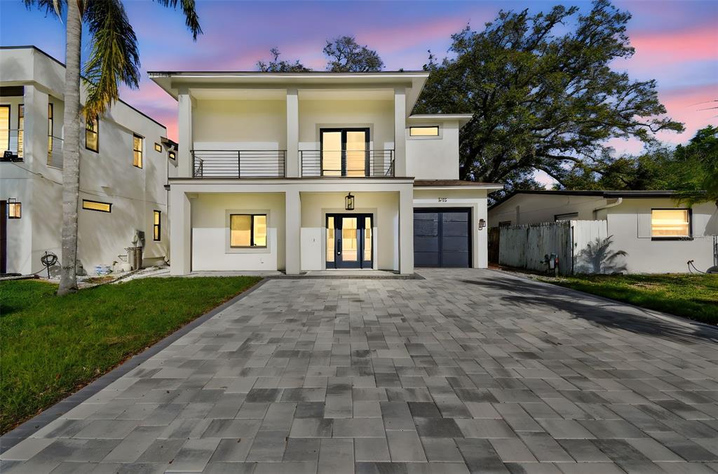 A modern two-story house with a paved driveway, balcony, and dark-framed windows at dusk — 1045 JESSE AVENUE, SAFETY HARBOR, FL