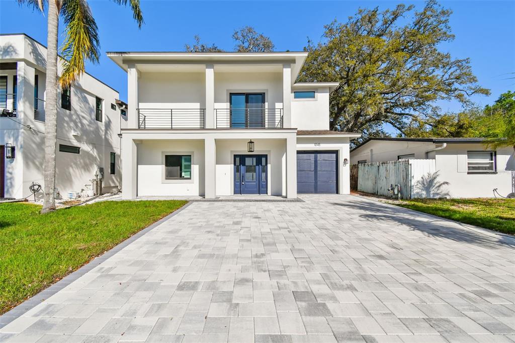 A modern two-story house with a paved driveway, blue front door, and a second-floor balcony — 1045 JESSE AVENUE, SAFETY HARBOR, FL