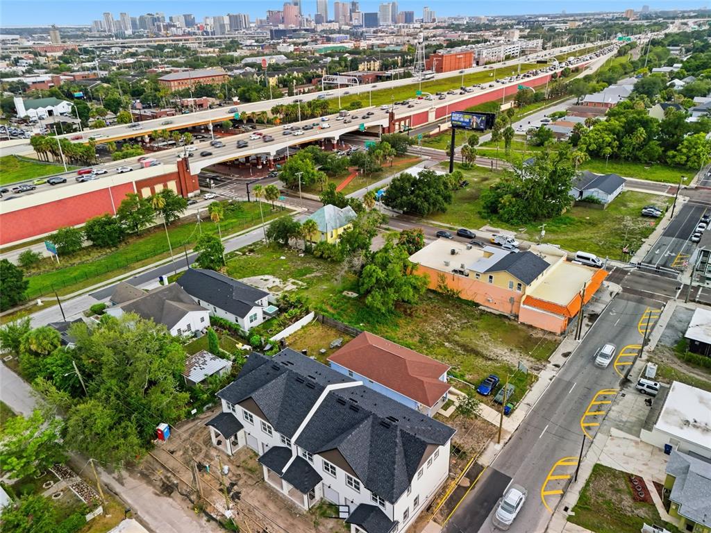 An aerial view shows a modern multi-unit residential building near a highway and city skyline — 2215 E COLUMBUS DRIVE, TAMPA, FL