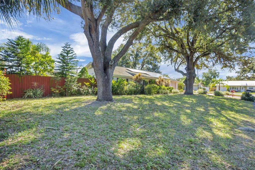 A grassy front yard features two large oak trees in front of a single-story house — 105 OWEN CIRCLE S, AUBURNDALE, FL
