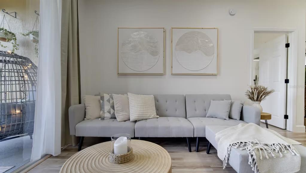 A living room features a light gray sofa, a round wooden coffee table, and wall art — 8103 COCONUT PALM WAY UNIT 203, KISSIMMEE, FL