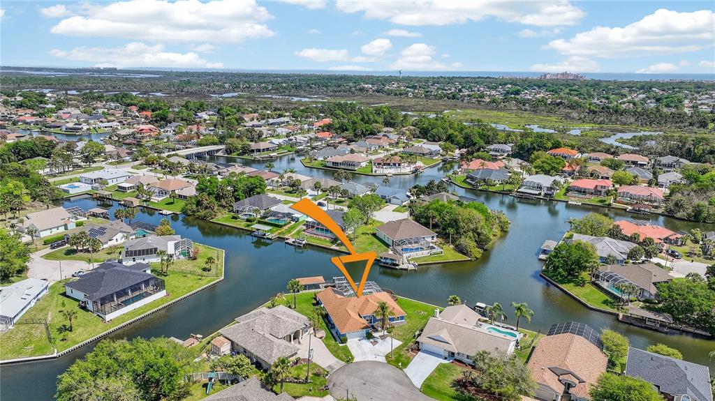 An aerial view shows a waterfront house with a pool cage and a cul-de-sac driveway — 20 CORONA COURT, PALM COAST, FL