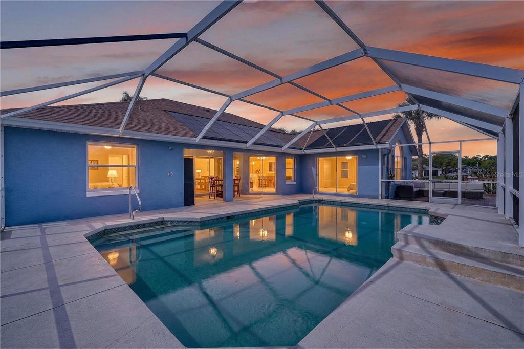 A blue house with a screened-in pool and patio at sunset — 20 CORONA COURT, PALM COAST, FL