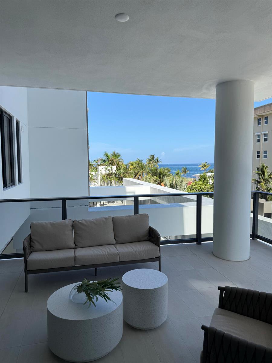 A covered balcony features a sofa, two round stone tables, and a view of the ocean — 305 Briny Avenue # 301, Pompano Beach FL 33062, POMPANO BEACH, FL