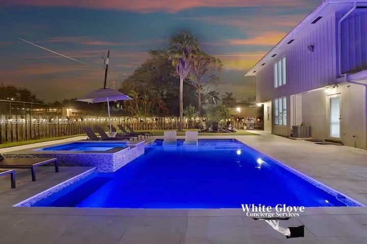 A modern swimming pool and hot tub are situated on a patio beside a house — 63 SE 5th Ave, Deerfield Beach FL 33441, DEERFIELD BEACH, FL