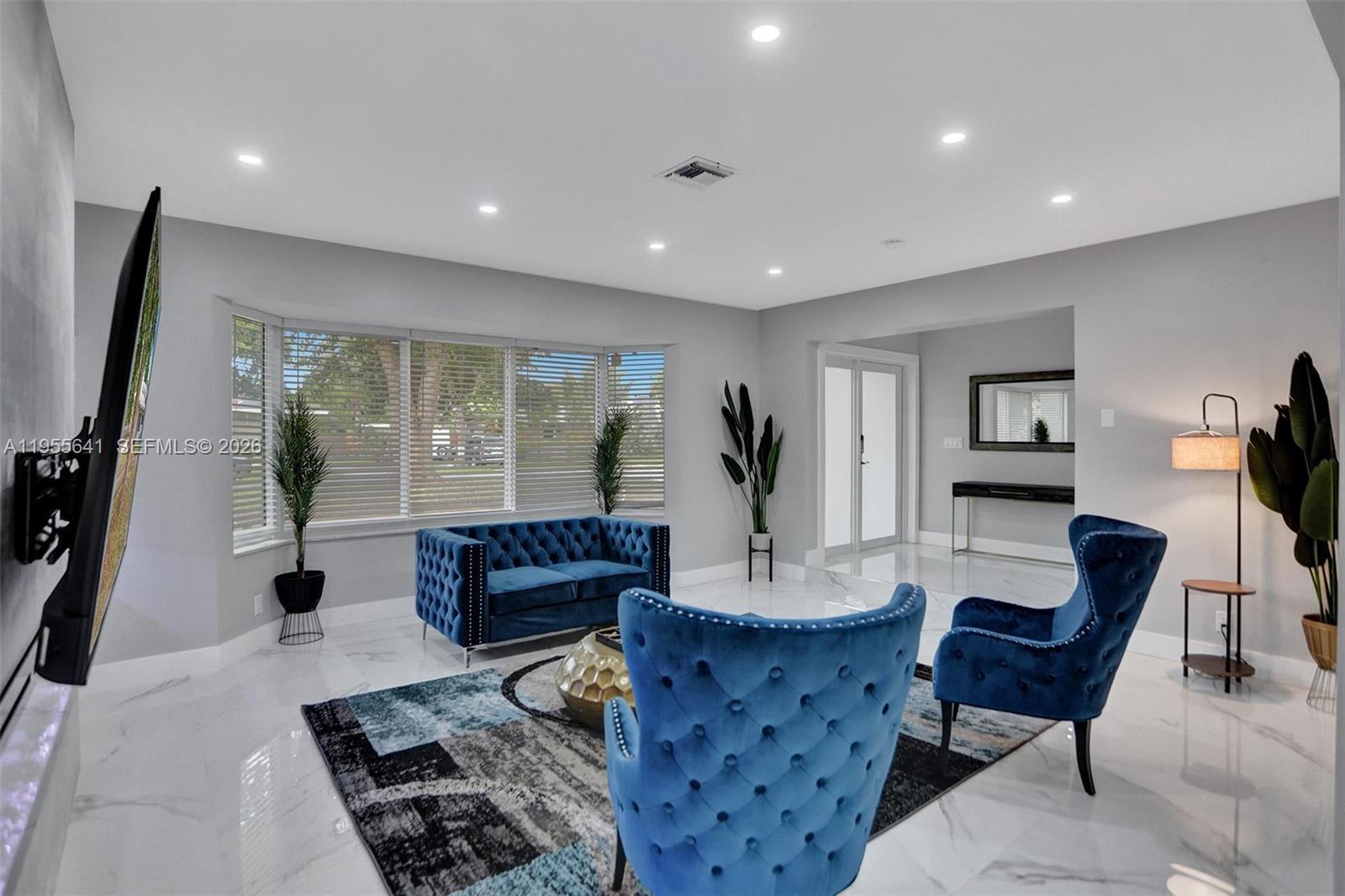 A living room features blue tufted furniture, a patterned rug, and white marble flooring — 63 SE 5th Ave, Deerfield Beach FL 33441, DEERFIELD BEACH, FL