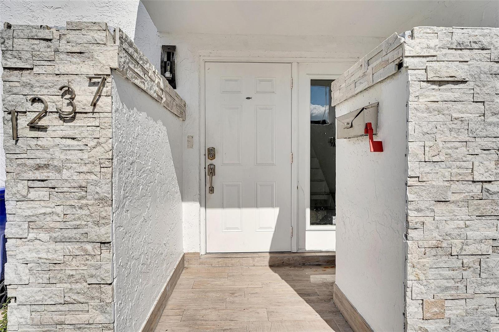 A white front door is centered between two stone-clad walls with a mailbox and house numbers — 1237 Seaview # 1237, North Lauderdale FL 33068, NORTH LAUDERDALE, FL