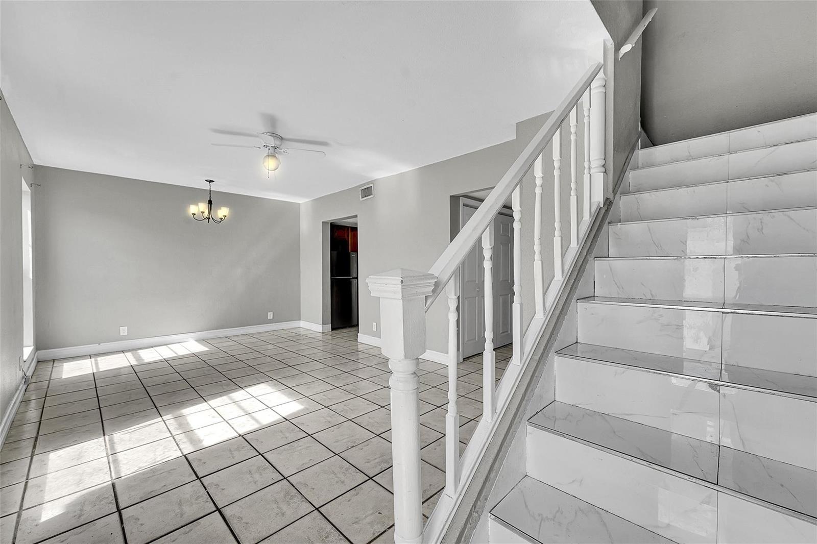A room with tiled floors and a staircase featuring white railings and marble-look steps — 1237 Seaview # 1237, North Lauderdale FL 33068, NORTH LAUDERDALE, FL