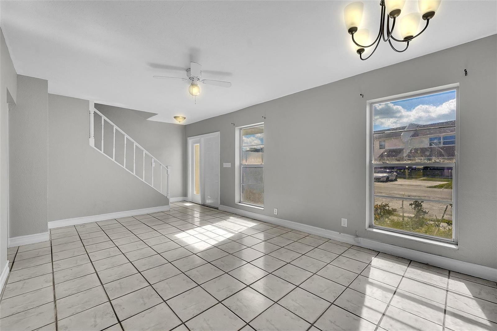 An empty room with white tile floors, a staircase, two windows, and a ceiling fan — 1237 Seaview # 1237, North Lauderdale FL 33068, NORTH LAUDERDALE, FL