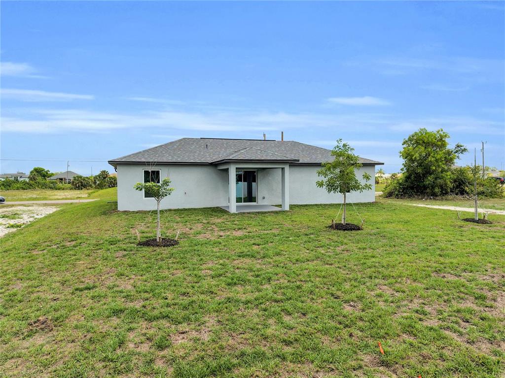 The exterior of a single-story house features a gray stucco finish and a covered patio — 1808 NE 44TH STREET, CAPE CORAL, FL
