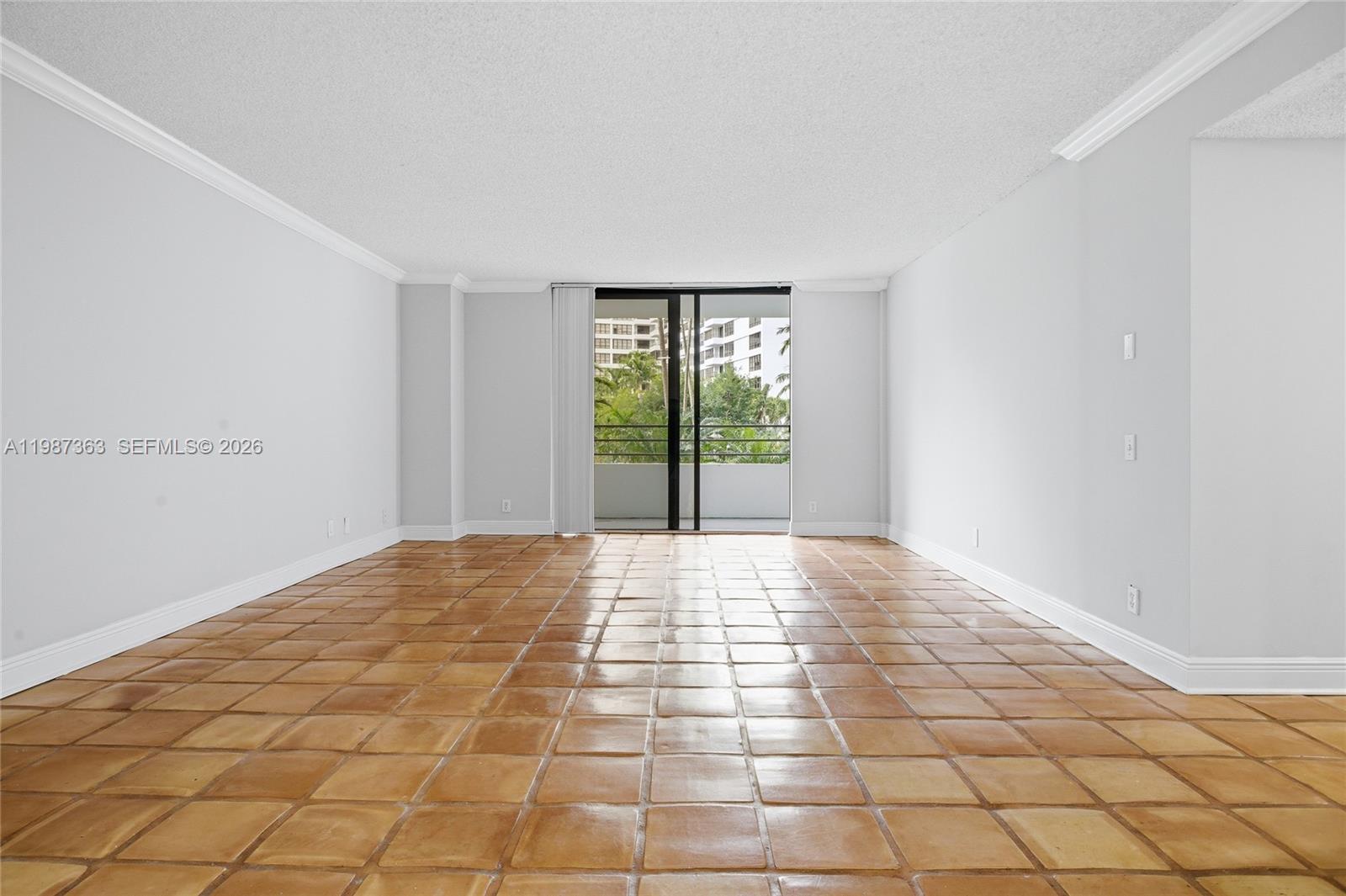An empty room features light-colored walls, crown molding, and brown square floor tiles — 2500 Parkview Dr # 415, Hallandale Beach FL 33009, HALLANDALE BEACH, FL