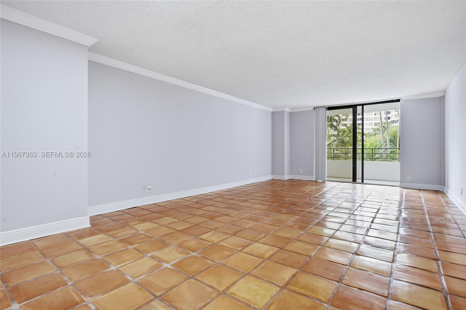 An empty living room features light gray walls, white crown molding, and terracotta tile flooring — 2500 Parkview Dr # 415, Hallandale Beach FL 33009, HALLANDALE BEACH, FL
