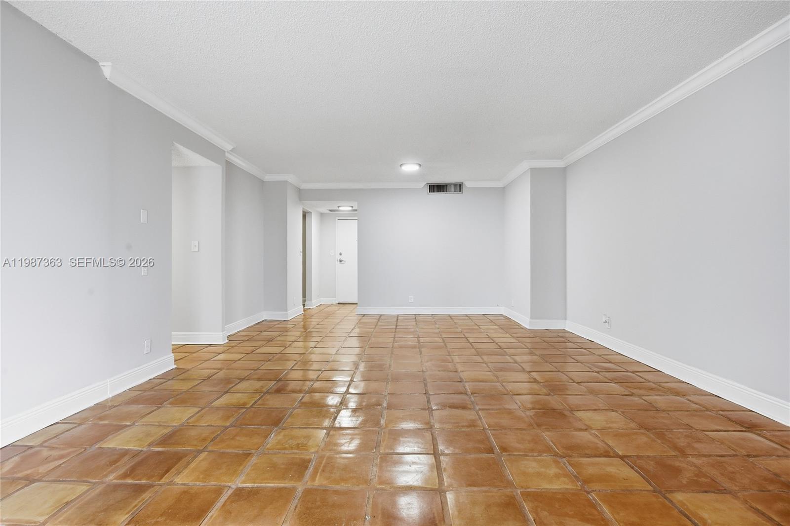 An empty room features light gray walls, white crown molding, and brown square floor tiles — 2500 Parkview Dr # 415, Hallandale Beach FL 33009, HALLANDALE BEACH, FL