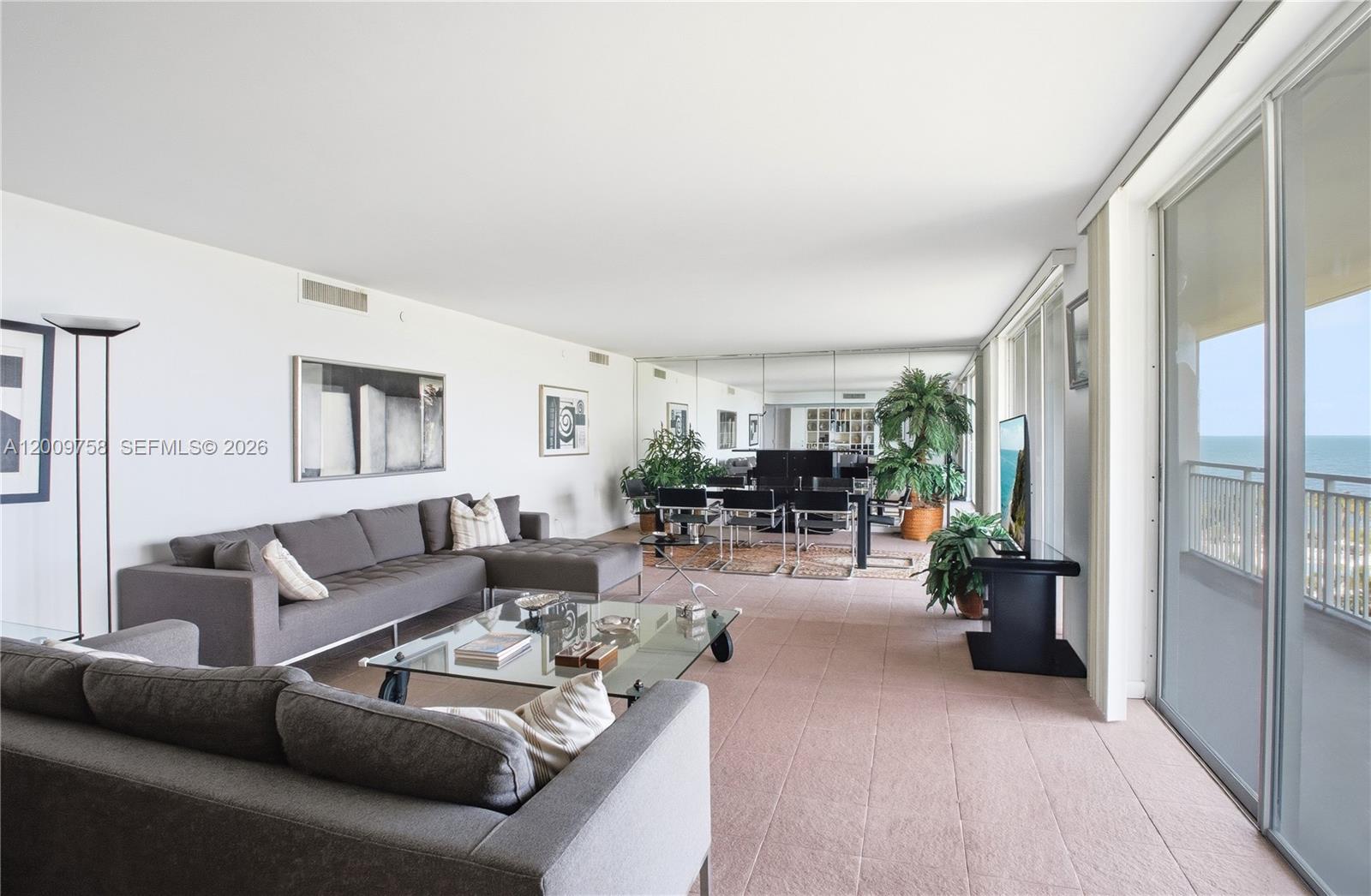 A living room with gray sofas, a glass coffee table, and a balcony overlooking the ocean — 605 Ocean Dr # 7L, Key Biscayne FL 33149, KEY BISCAYNE, FL