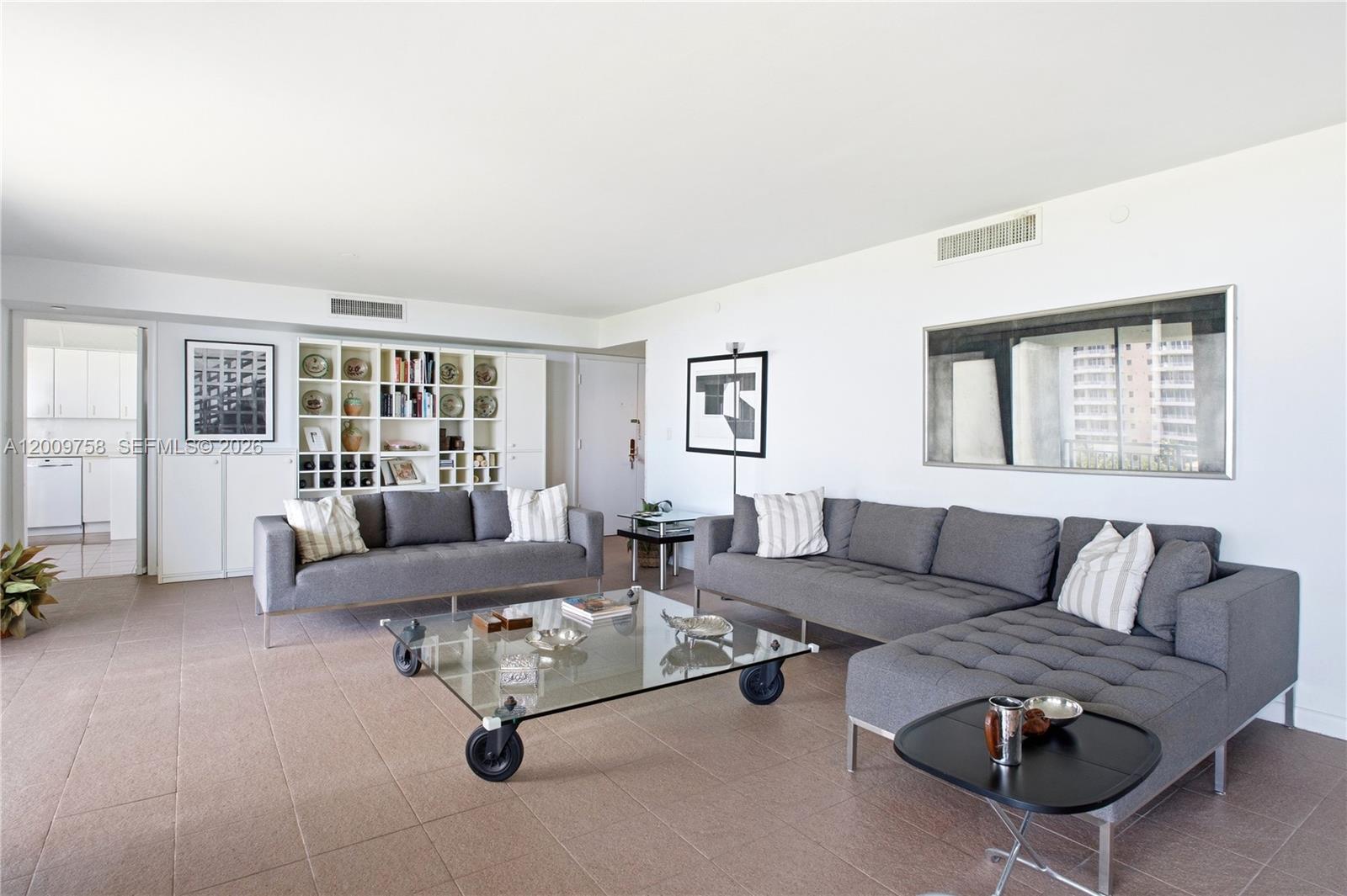 A living room features two gray sofas, a glass coffee table, and built-in shelving — 605 Ocean Dr # 7L, Key Biscayne FL 33149, KEY BISCAYNE, FL