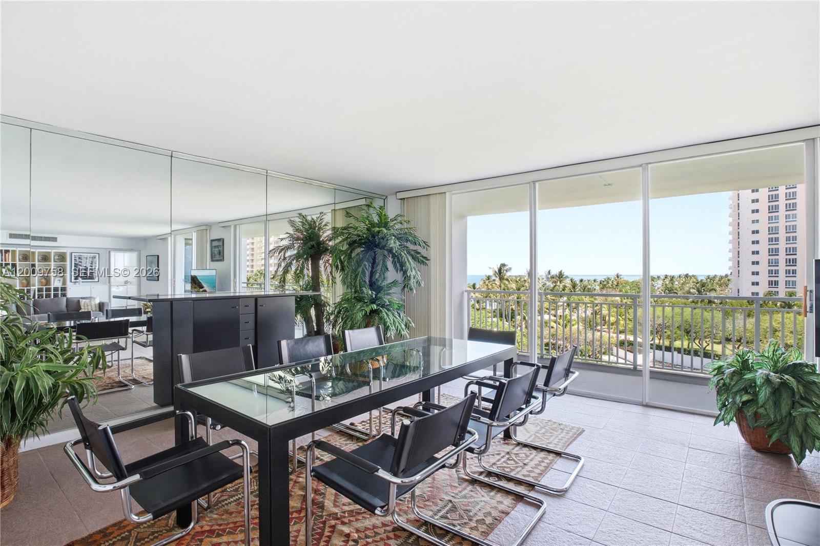 A dining room features a glass-topped table, black chairs, mirrored walls, and a balcony view — 605 Ocean Dr # 7L, Key Biscayne FL 33149, KEY BISCAYNE, FL