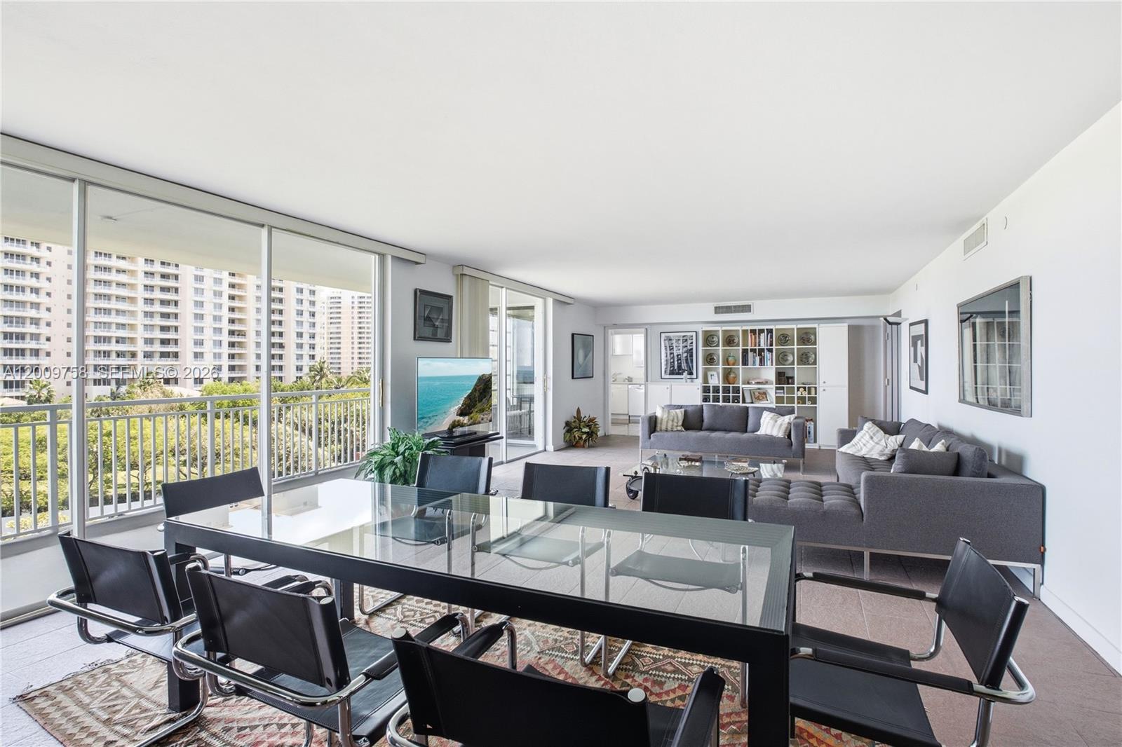 A spacious living and dining area features a glass table, gray sofas, and balcony views — 605 Ocean Dr # 7L, Key Biscayne FL 33149, KEY BISCAYNE, FL