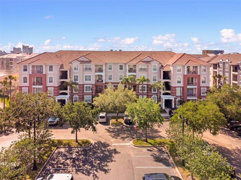 An exterior view of a multi-story apartment building with a parking lot in front — 4862 CAYVIEW AVENUE UNIT 407, ORLANDO, FL