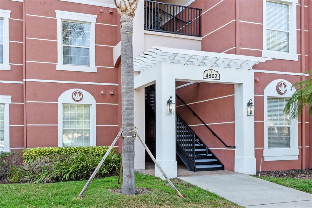 An exterior view of a multi-story apartment building with a staircase and a pergola entrance — 4862 CAYVIEW AVENUE UNIT 407, ORLANDO, FL