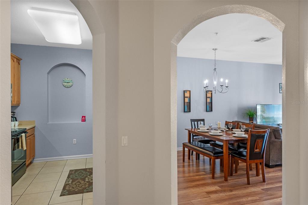 A view through arched doorways into a kitchen and a dining room with wood flooring — 4862 CAYVIEW AVENUE UNIT 407, ORLANDO, FL